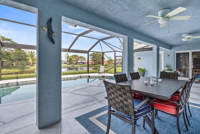 view of patio with a water view, ceiling fan, and glass enclosure