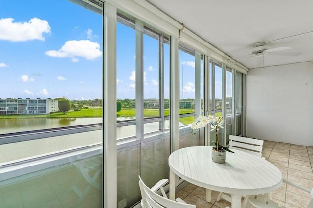 sunroom / solarium with ceiling fan and a water view