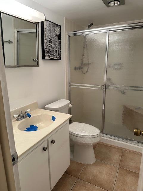 bathroom featuring vanity, an enclosed shower, tile patterned floors, and toilet