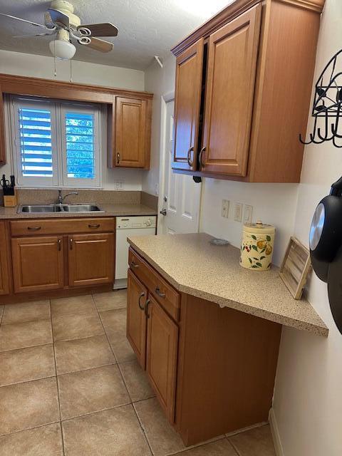 kitchen with sink, light tile patterned floors, ceiling fan, white dishwasher, and a textured ceiling