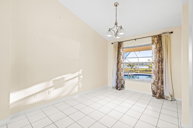 tiled empty room with lofted ceiling and a notable chandelier