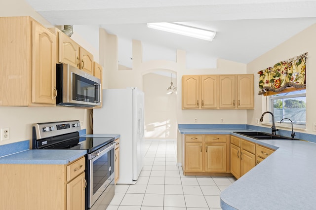 kitchen featuring lofted ceiling, sink, light tile patterned floors, appliances with stainless steel finishes, and light brown cabinetry