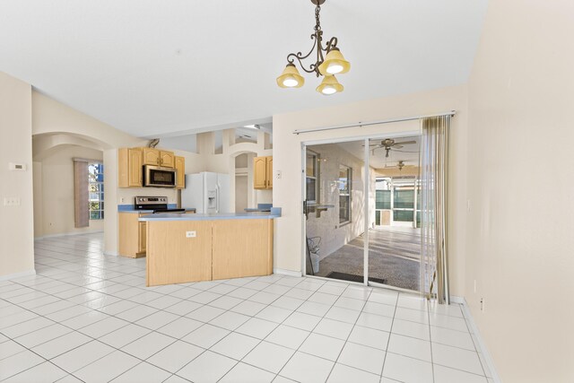 kitchen featuring pendant lighting, light tile patterned floors, stainless steel appliances, light brown cabinetry, and vaulted ceiling