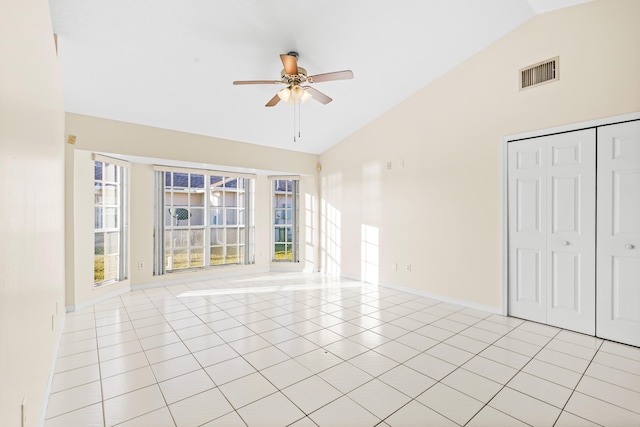 empty room with lofted ceiling, light tile patterned floors, and ceiling fan