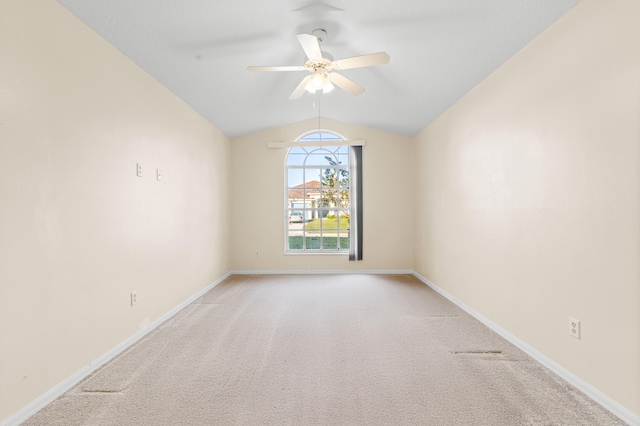 spare room featuring ceiling fan, vaulted ceiling, and light carpet