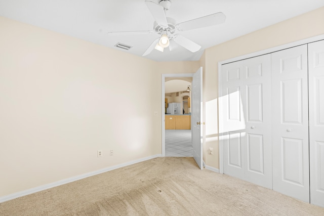 unfurnished bedroom featuring ceiling fan, a closet, and light carpet