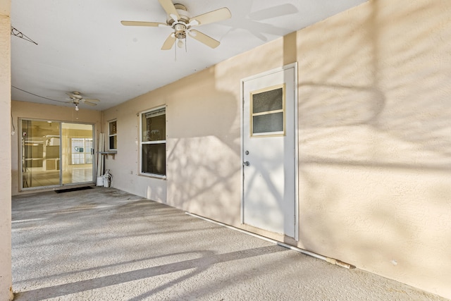 view of exterior entry with ceiling fan and a patio