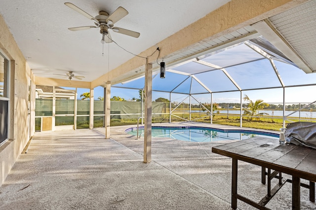 view of swimming pool featuring a water view, ceiling fan, a patio, and glass enclosure