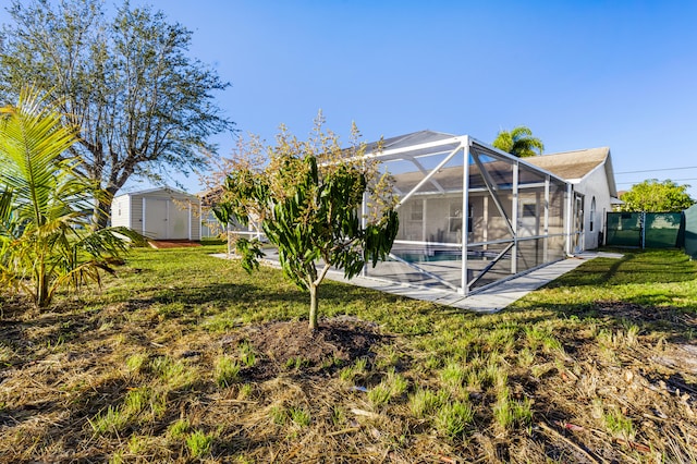 back of property featuring a patio, a yard, glass enclosure, and a shed