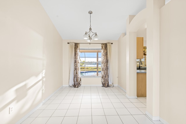 tiled spare room featuring a notable chandelier and vaulted ceiling