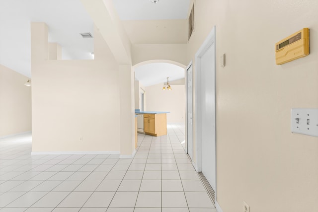 hall with light tile patterned floors and an inviting chandelier