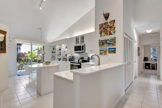 kitchen featuring vaulted ceiling, tasteful backsplash, light tile patterned floors, stainless steel appliances, and a textured ceiling