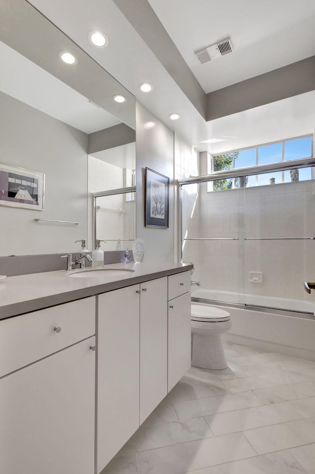 full bathroom with toilet, vanity, and bath / shower combo with glass door