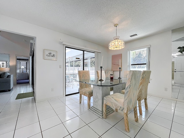 tiled dining area with a notable chandelier and a textured ceiling