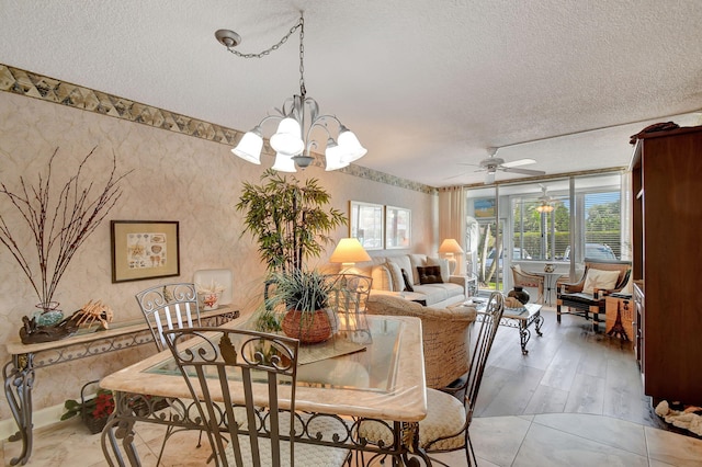 dining area with ceiling fan with notable chandelier and a textured ceiling