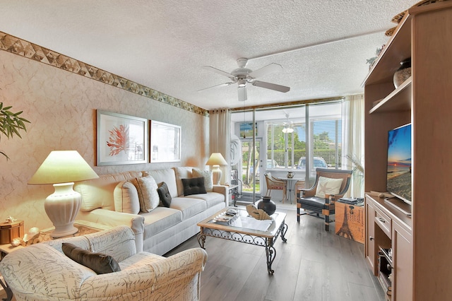 living room with hardwood / wood-style flooring, ceiling fan, and a textured ceiling