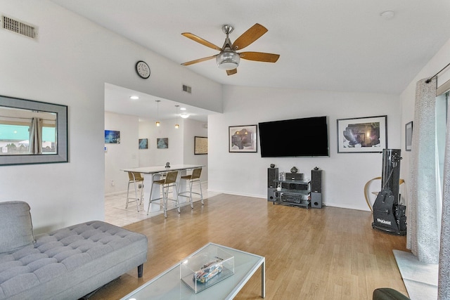 living room featuring ceiling fan, lofted ceiling, and light hardwood / wood-style flooring