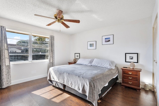 bedroom with ceiling fan, dark wood-type flooring, and a textured ceiling