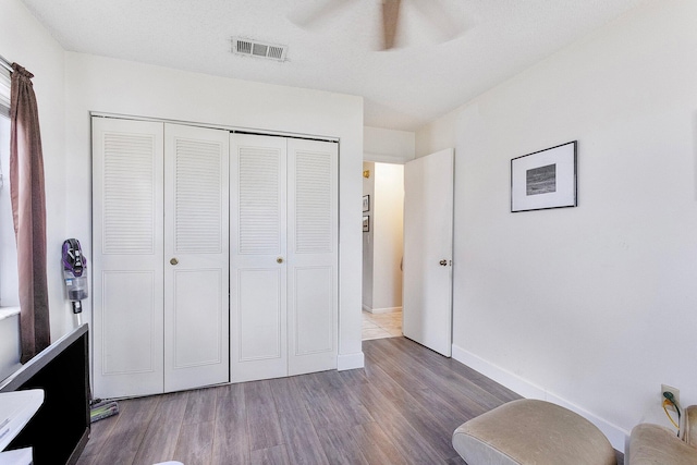 unfurnished bedroom featuring wood-type flooring, ceiling fan, and a closet