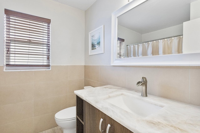 bathroom with vanity, toilet, and tile walls