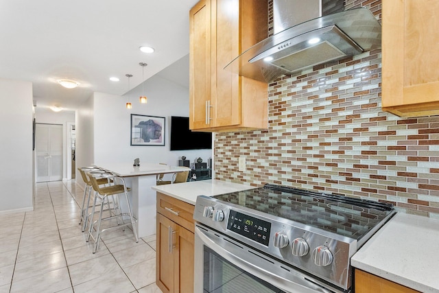 kitchen featuring pendant lighting, wall chimney range hood, a kitchen breakfast bar, tasteful backsplash, and stainless steel range with electric cooktop