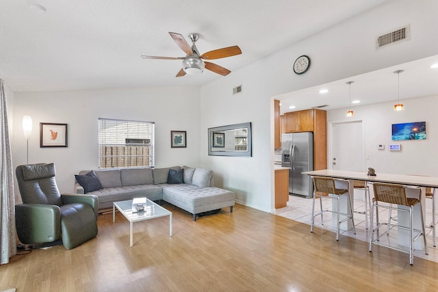 living room with ceiling fan, lofted ceiling, and light hardwood / wood-style floors