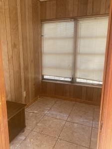 interior space with tile patterned floors and wooden walls