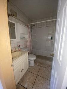 bathroom featuring vanity, a shower, tile patterned floors, and toilet