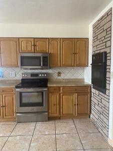 kitchen with backsplash, light tile patterned floors, and stainless steel appliances