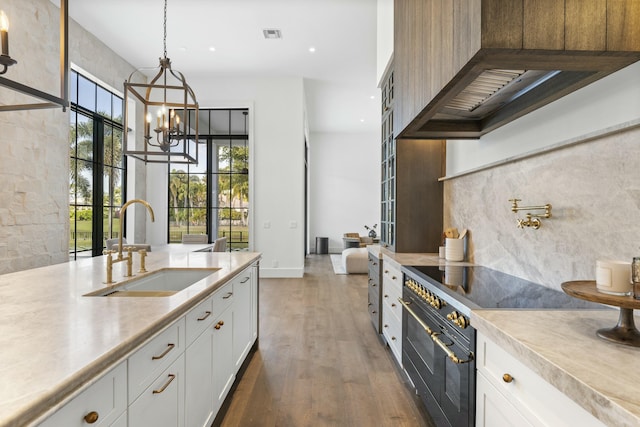 kitchen with range with two ovens, sink, pendant lighting, and white cabinets