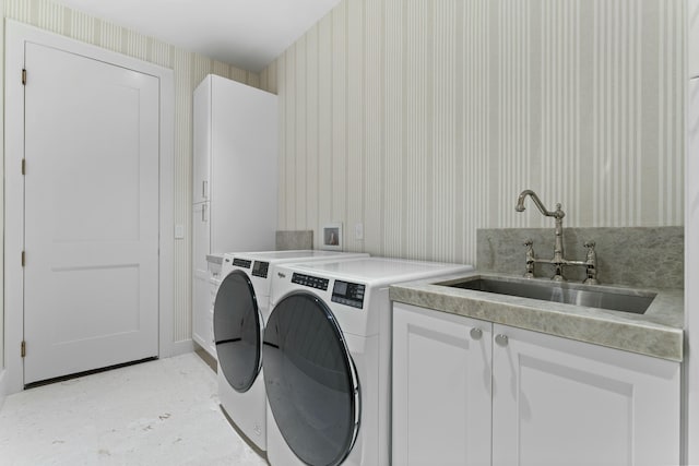 clothes washing area with cabinets, sink, and washer and clothes dryer