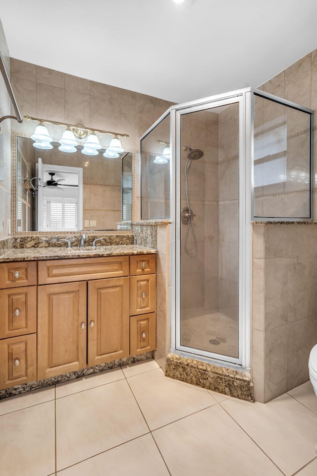 bathroom with tile walls, vanity, tile patterned flooring, and a shower with door