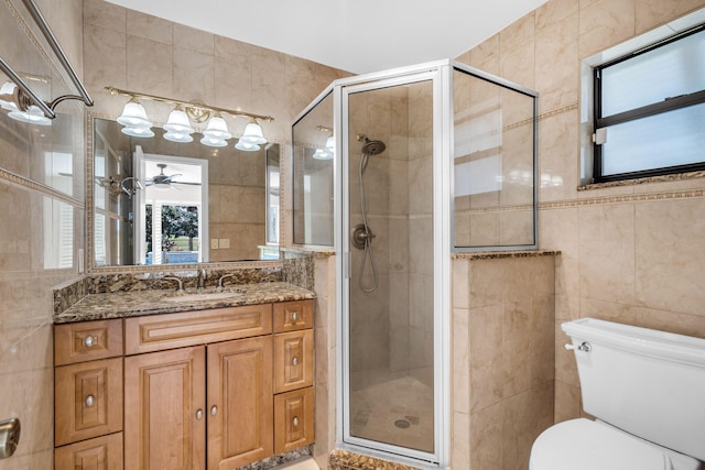 bathroom with tile walls, an enclosed shower, vanity, and toilet