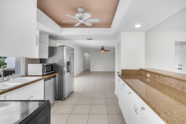 kitchen featuring appliances with stainless steel finishes, white cabinets, light tile patterned floors, ceiling fan, and a raised ceiling