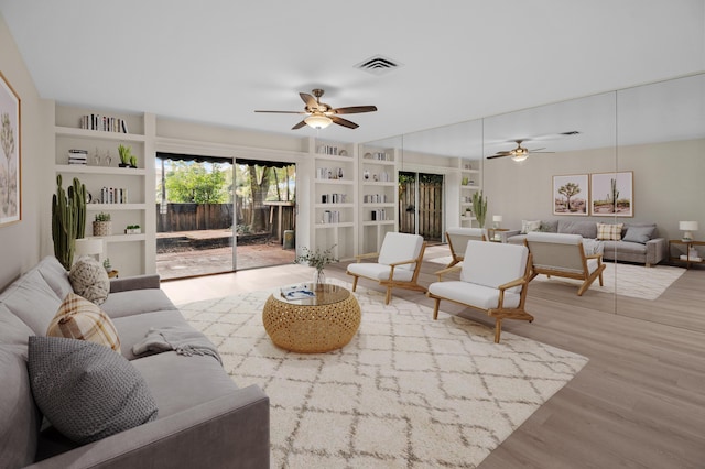 living room featuring built in shelves, ceiling fan, and hardwood / wood-style floors