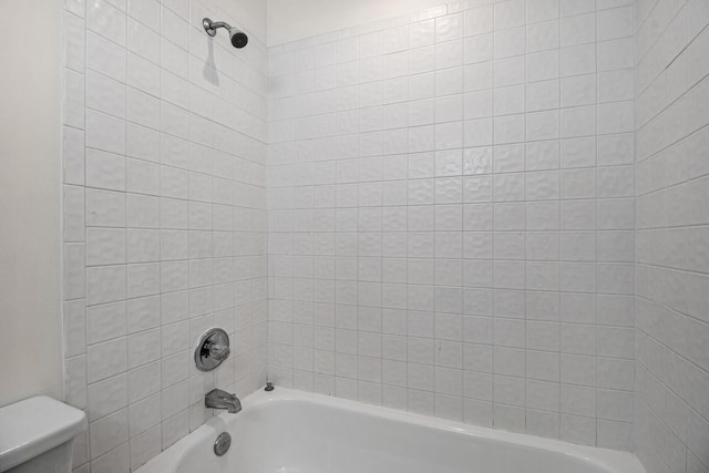 bathroom featuring tiled shower / bath and toilet