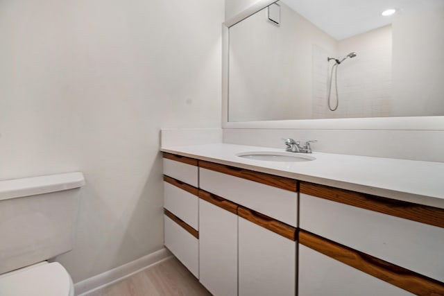 bathroom with vanity, hardwood / wood-style floors, toilet, and tiled shower