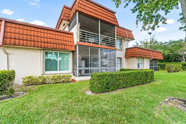 rear view of house featuring a yard and a sunroom