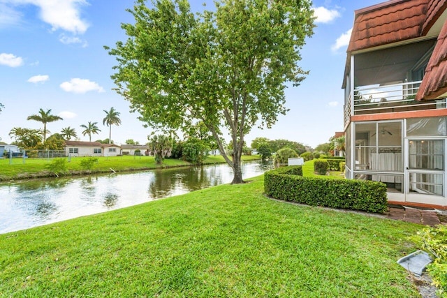 view of yard with a sunroom and a water view