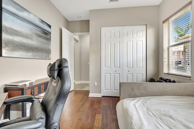 bedroom with dark hardwood / wood-style flooring and a closet