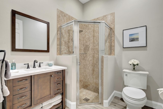 bathroom featuring vanity, hardwood / wood-style floors, a shower with shower door, and toilet