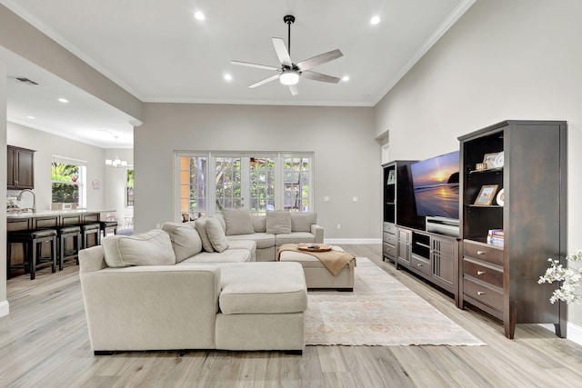 living room with sink, crown molding, light hardwood / wood-style flooring, and ceiling fan with notable chandelier