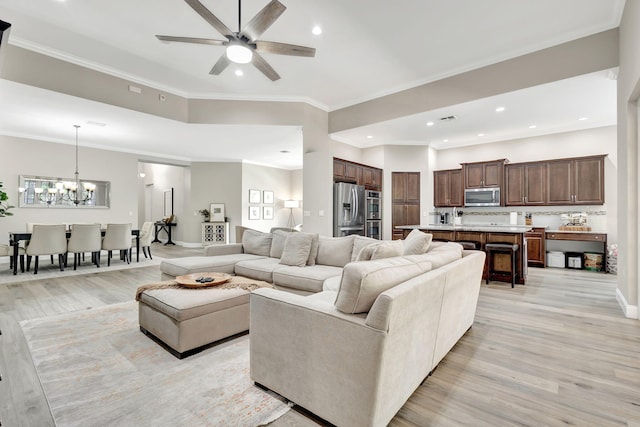 living room featuring ceiling fan with notable chandelier, ornamental molding, and light hardwood / wood-style floors