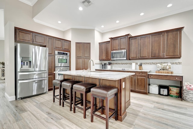 kitchen with sink, backsplash, a center island with sink, and appliances with stainless steel finishes