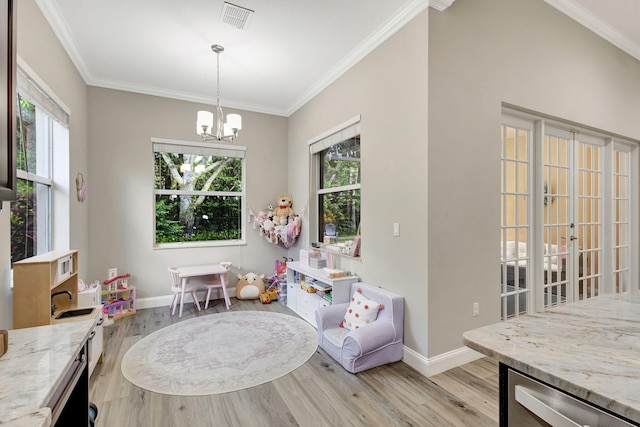 rec room with light hardwood / wood-style flooring, ornamental molding, and a chandelier