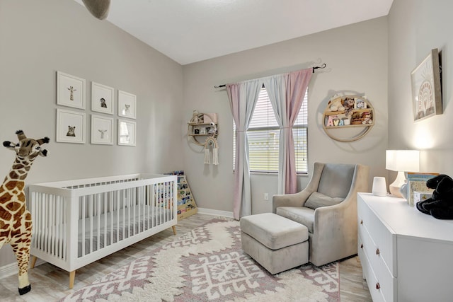 bedroom with a nursery area and light hardwood / wood-style floors