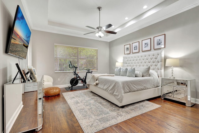 bedroom with crown molding, a tray ceiling, ceiling fan, and hardwood / wood-style flooring