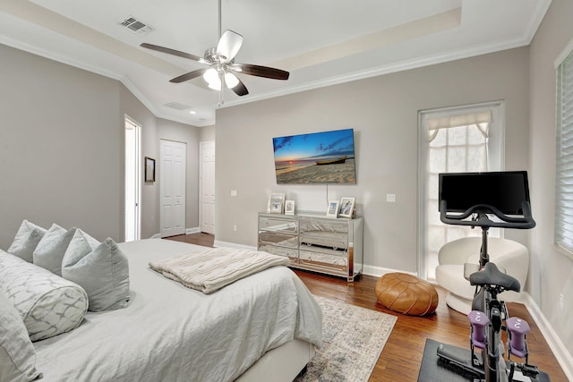 bedroom with ornamental molding, ceiling fan, dark hardwood / wood-style flooring, and a tray ceiling