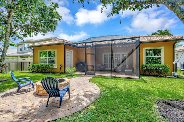 back of property featuring a fire pit, ceiling fan, a yard, glass enclosure, and a patio area