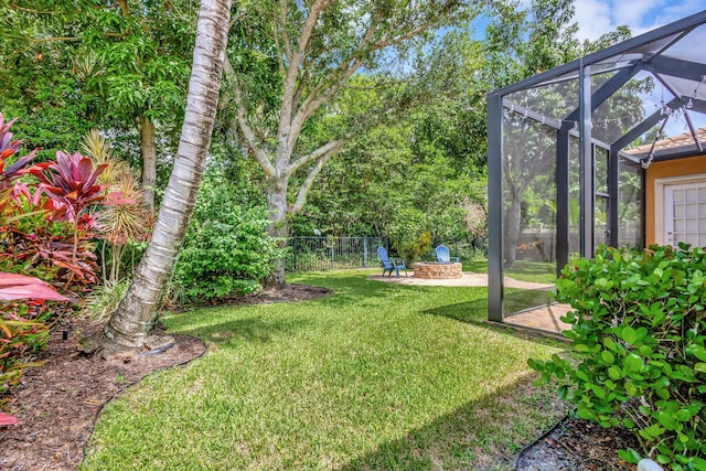 view of yard featuring a lanai, a patio area, and an outdoor fire pit